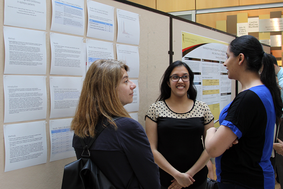 Three students stand in front of a large poster board discussing research in the Ellen H. Yankellow Grand Atrium