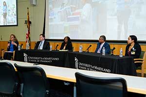 5 panelists at a table in the front of a lecture hall