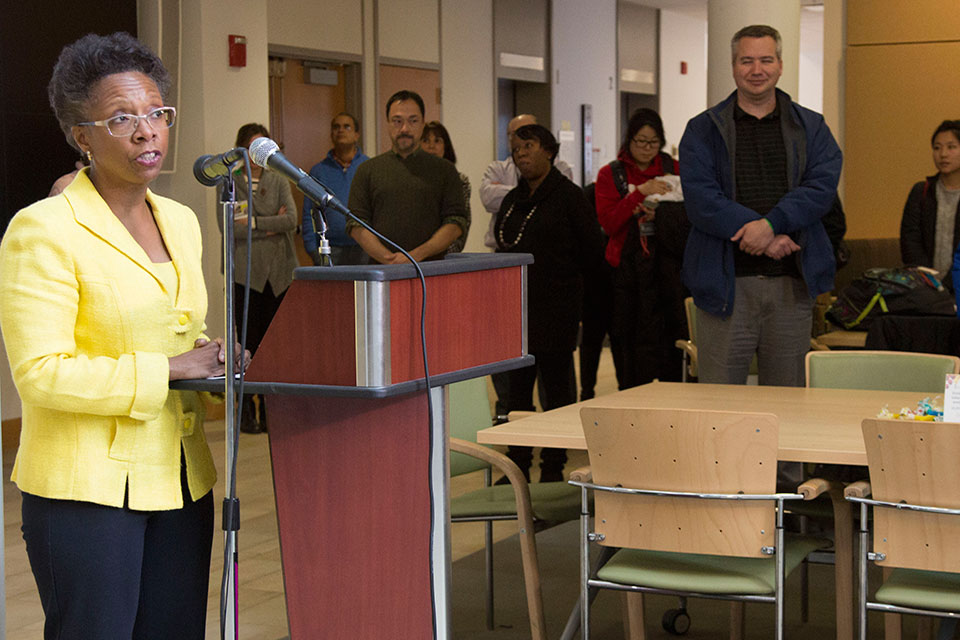 Dean Natalie Eddington speaks at the lectern with people in the background watching.