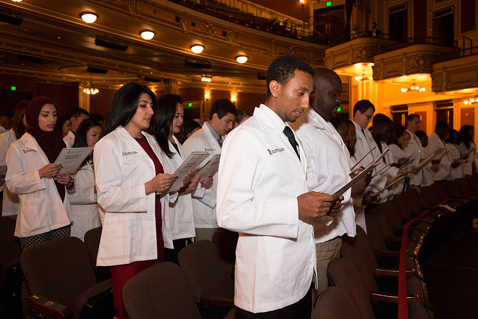 Students in white recite the Pledge of Professionalism