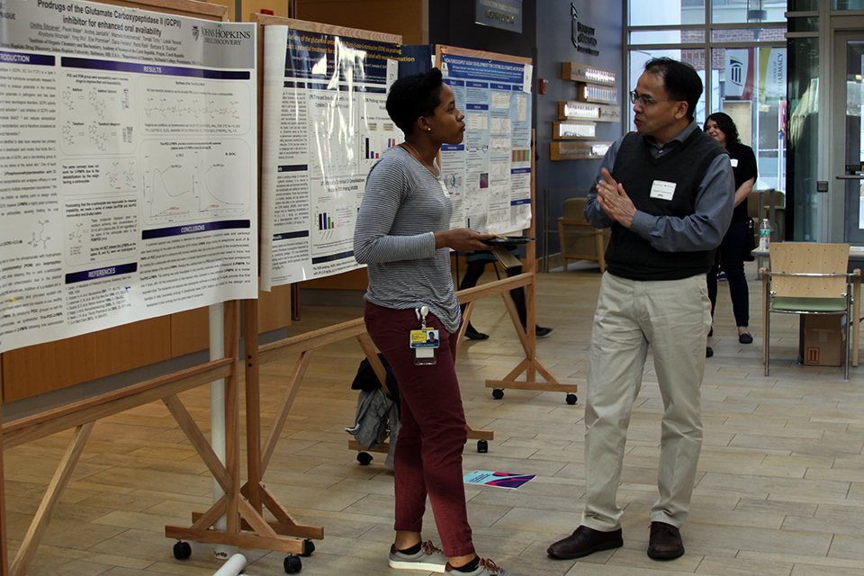 Student Presents Her Work to Dr. Tsukamoto During Symposium's Poster Session