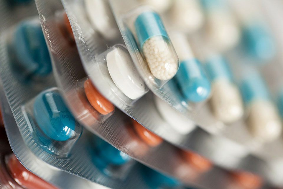 Blue, White, and Orange Pills Stacked Together in Original Packaging