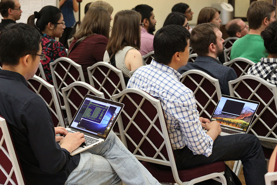 Audience members take notes on their laptops while listening to presentations during CADD Symposium.