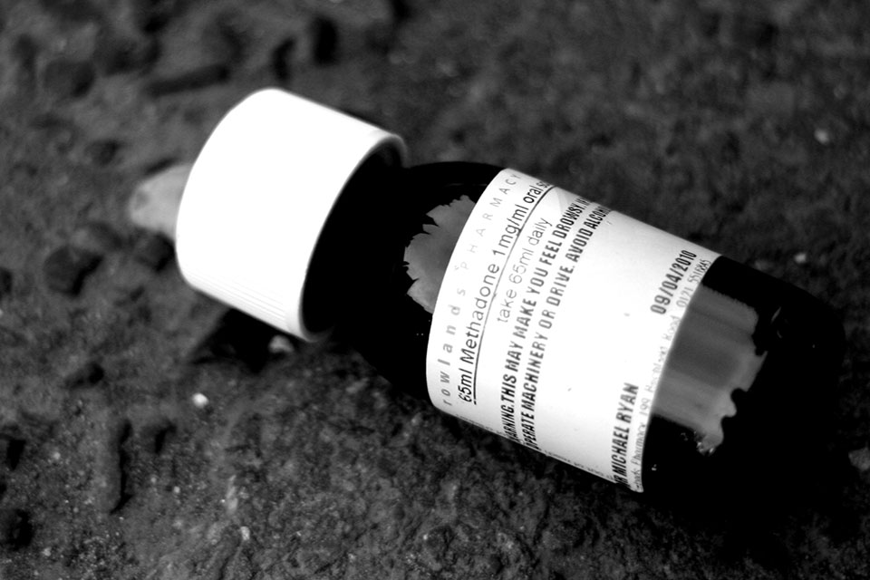 Bottle of methadone oral solution against a black background.