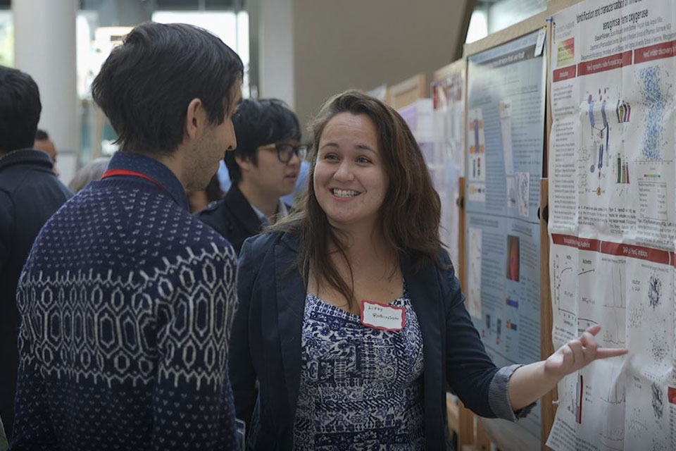 Graduate student Elizabeth Robinson explains her research to another symposium attendee.