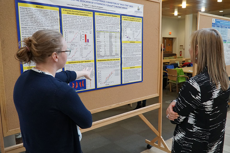 Graduate student discusses her research with a symposium attendee during the event's poster session.