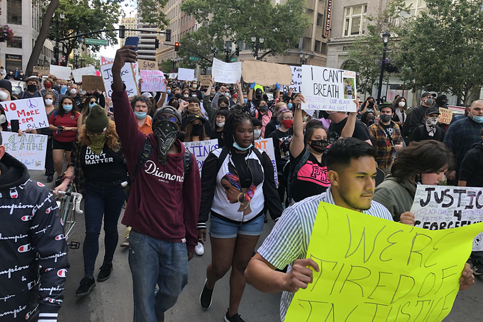 Individuals march down a street in protest of the death of George Floyd.