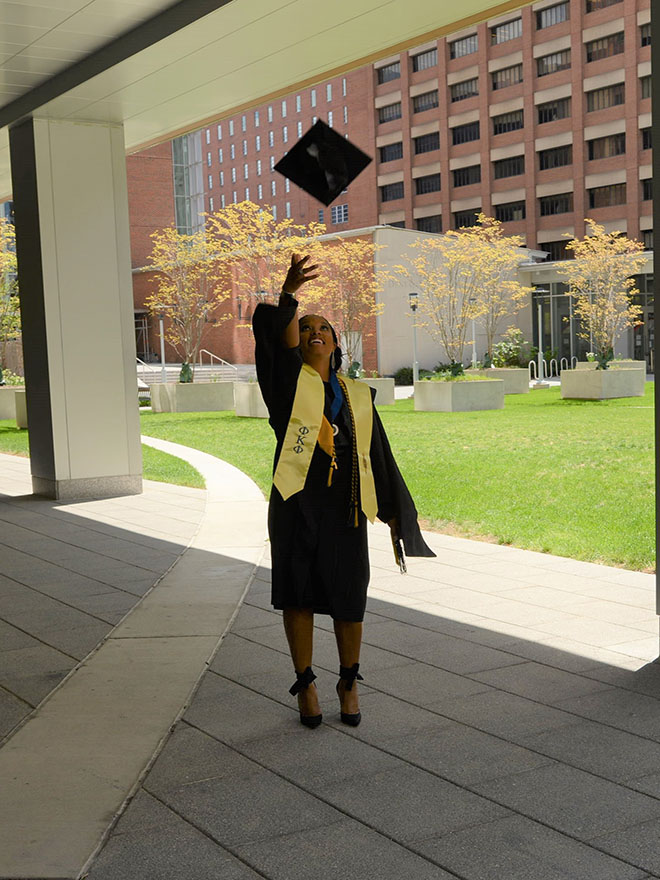 Graduate student tosses her graduation cap in the air.