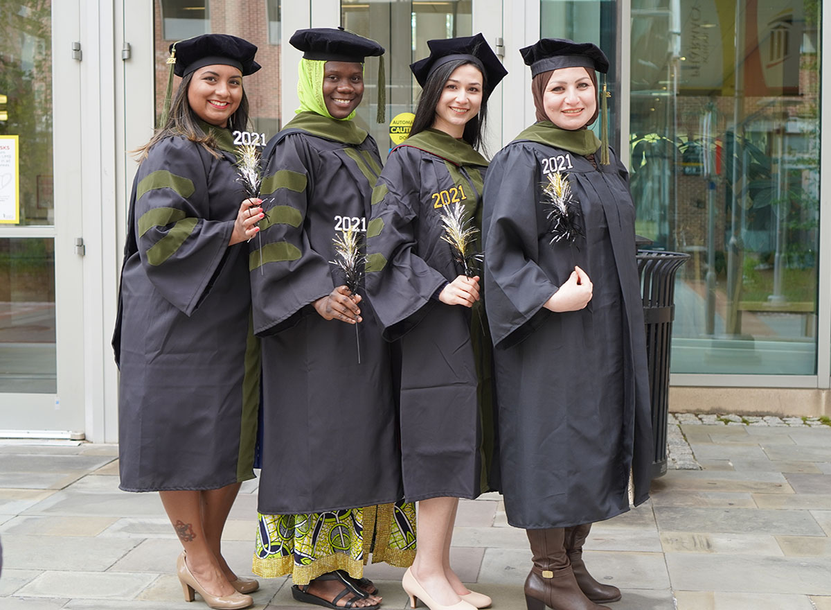 Four student pharmacists pose for photo in graduation regalia.