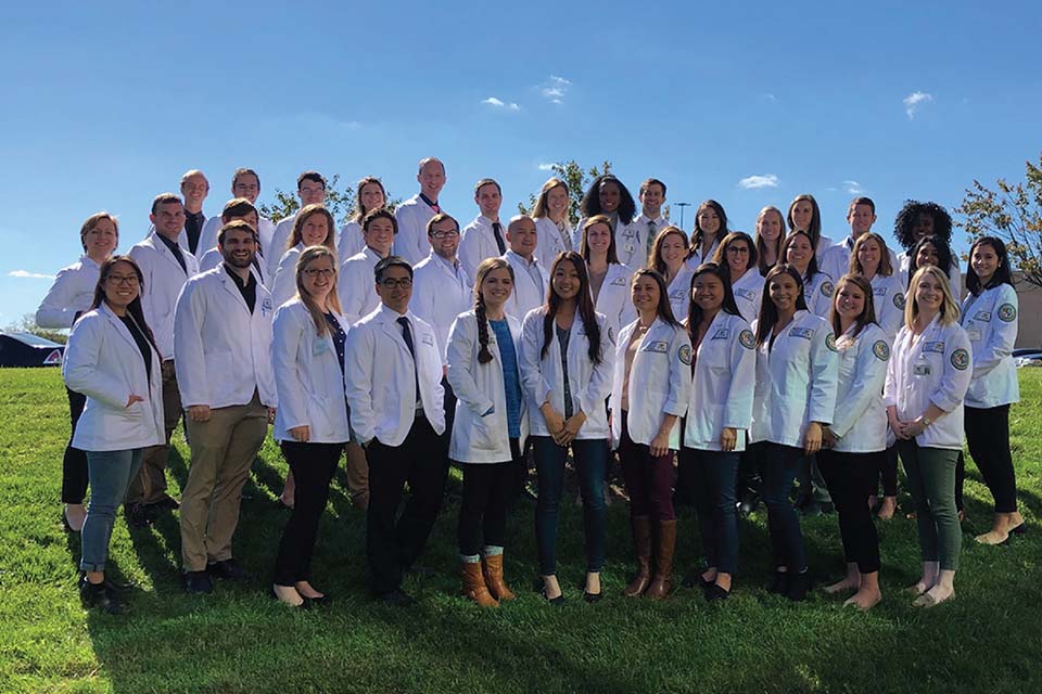 Cohort of students wearing white coats