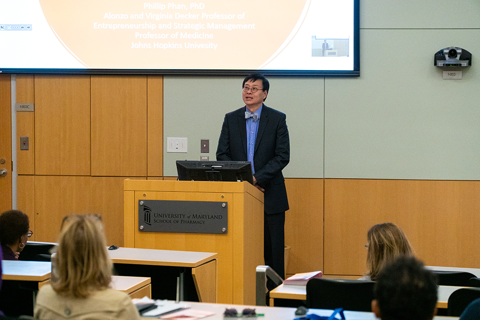 Phillip Phan speaks at a lectern in a lecture hall.