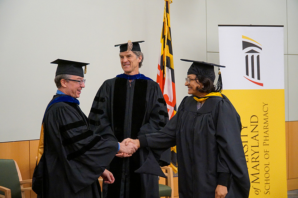 A student is congratulated by faculty at the regulatory science graduation