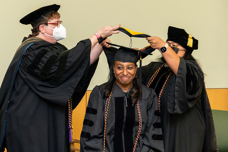 A student gets hooded at the 2022 palliative care graduation.