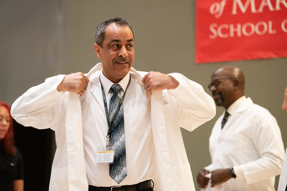 A student puts on his white coat.