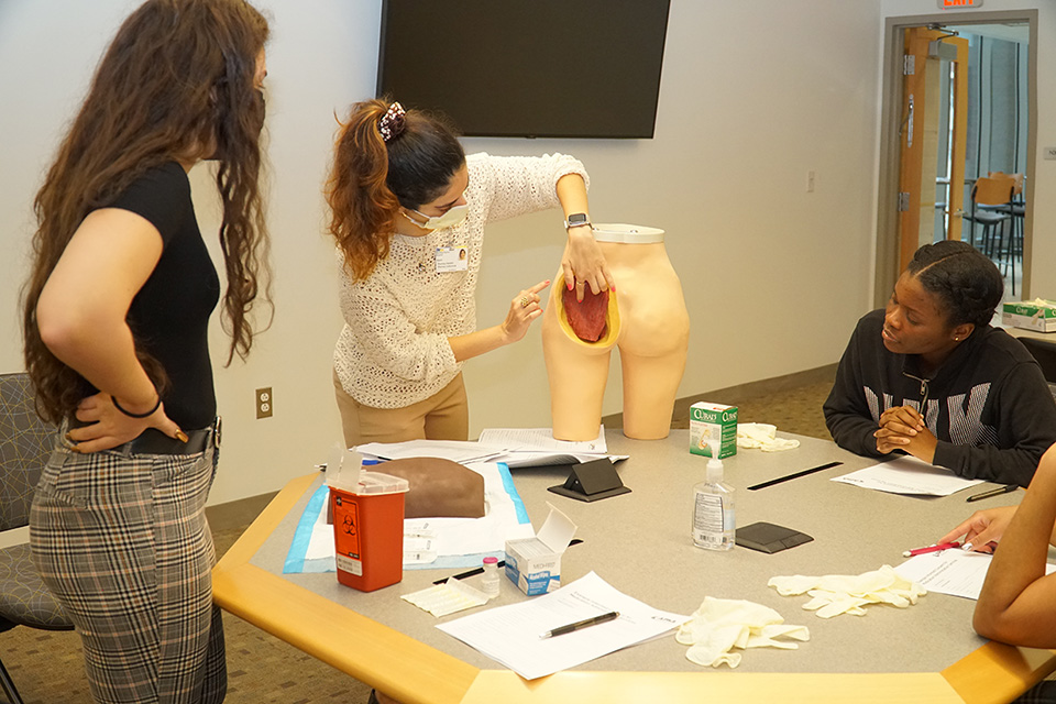 A student works on a model to practice giving injections.