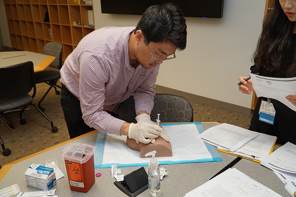 A student practices giving an injection.
