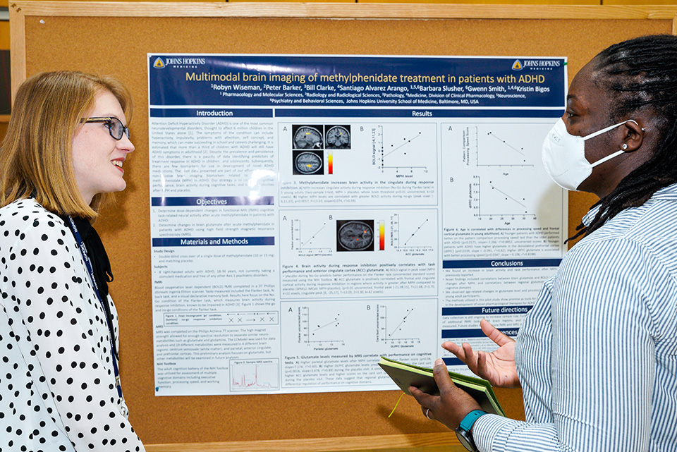 A student explaining their poster at the UMB-JHU Drug Discovery Symposium