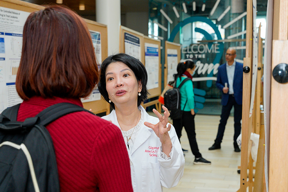 Two people engaged in conversation during the poster session at the UMB-JHU Drug Discovery Symposium