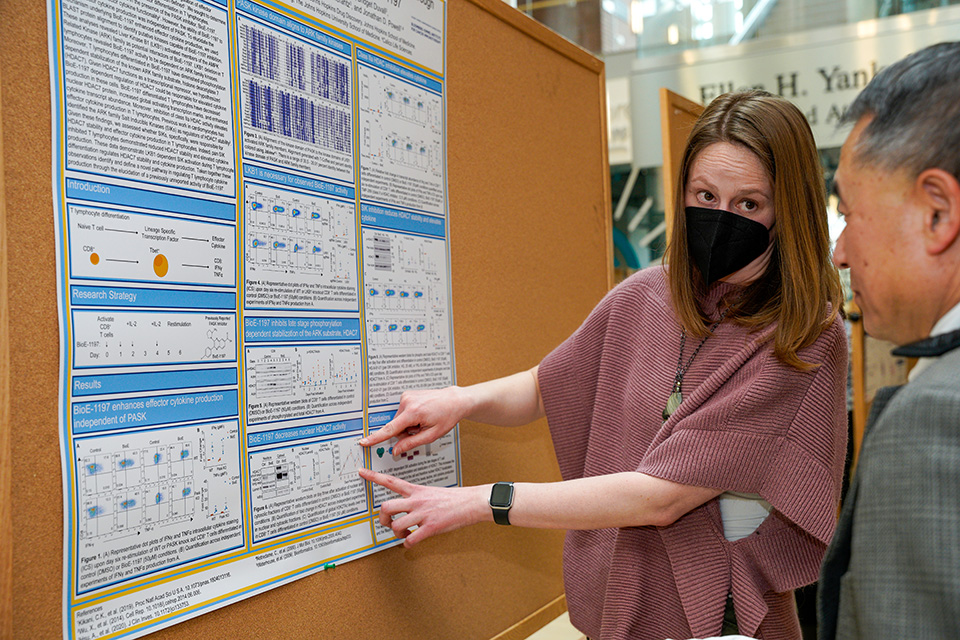 A student explains a poster at the UMB-JHU Drug Discovery Symposium