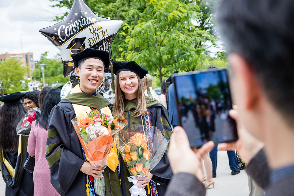 Two students holding bouquets after the PharmD graduation.