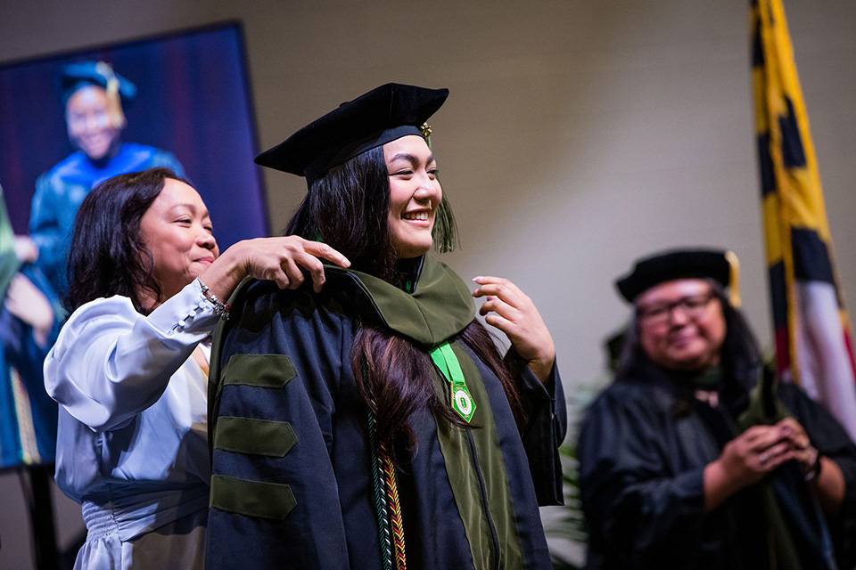 A student smiles while being hooded.