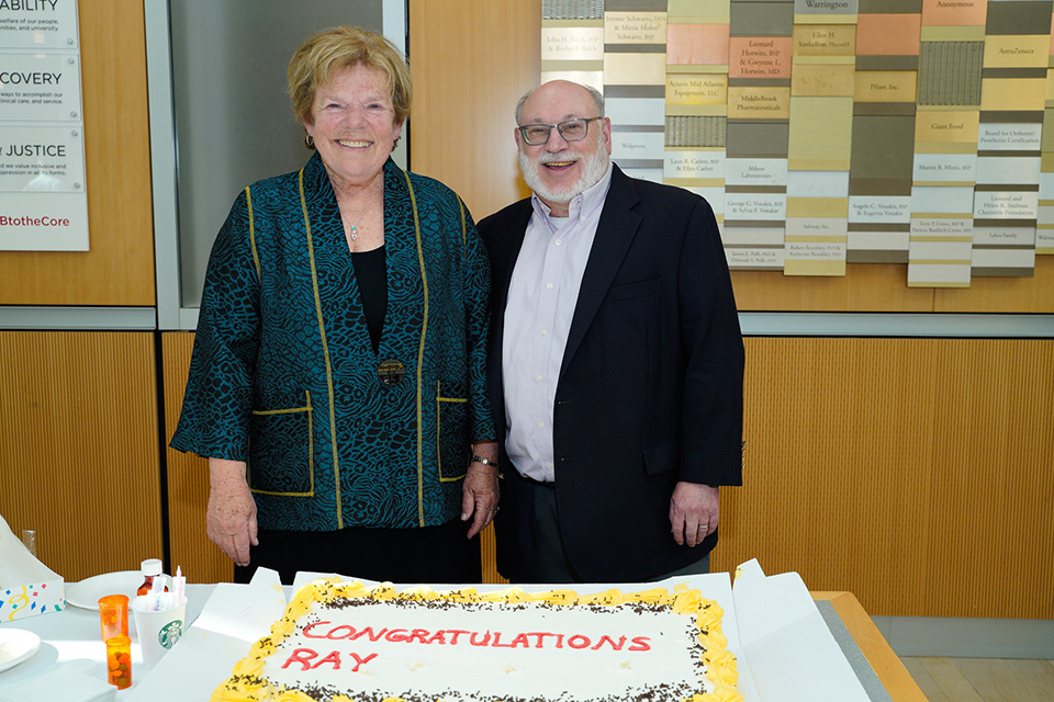 Raymond Love and Cynthia Boyle smile in front of a cake for his retirement.