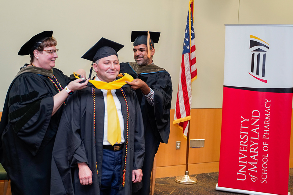 A student receives their hood during the palliative care graduation.