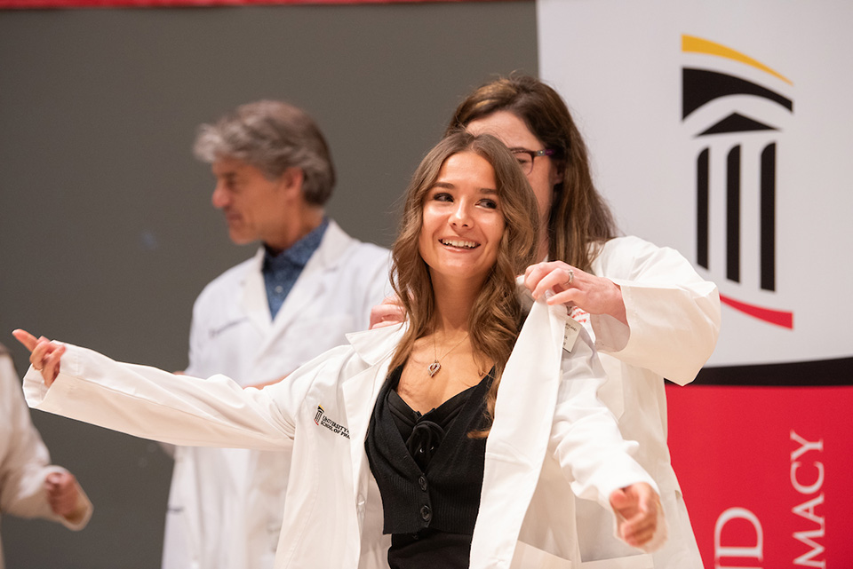 A student receives their white coat.