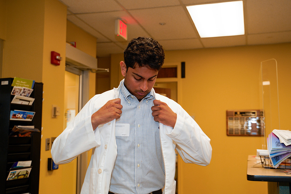 A new PharmD student tries on a white coat.