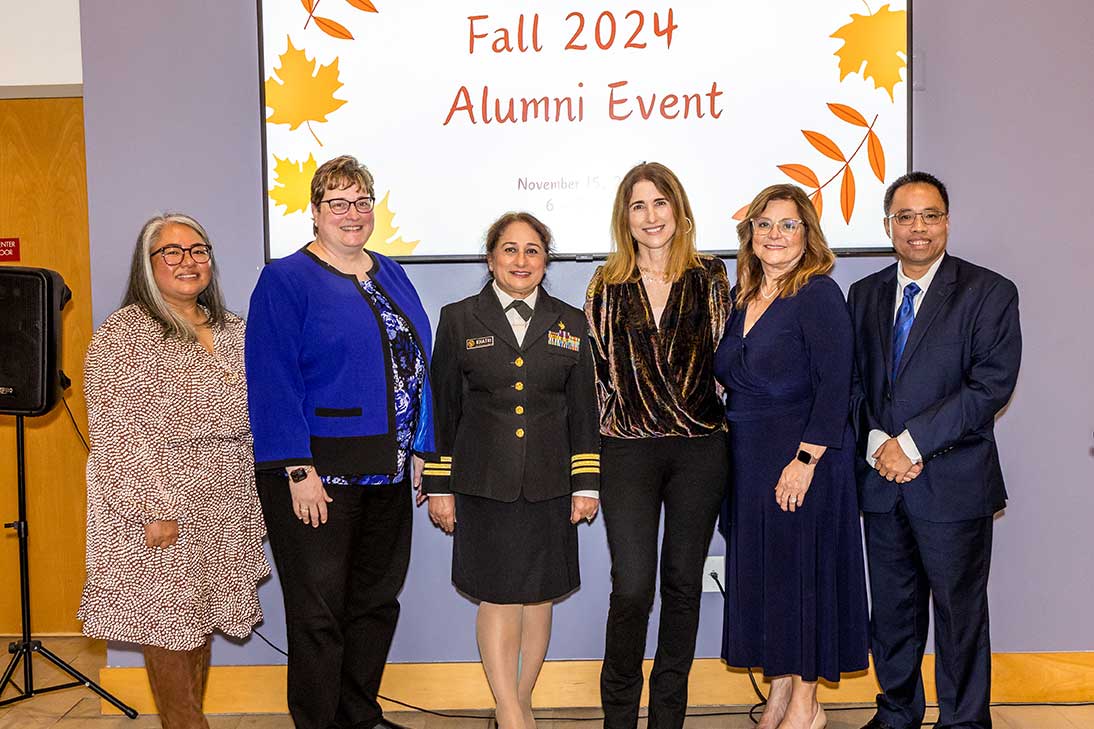 Cherokee Layson-Wolf, Jill Morgan, Sadhna Khatri, Dean Sarah Michel, Magaly Rodriguez Bittner, and presenter standing at the Alumni Gathering