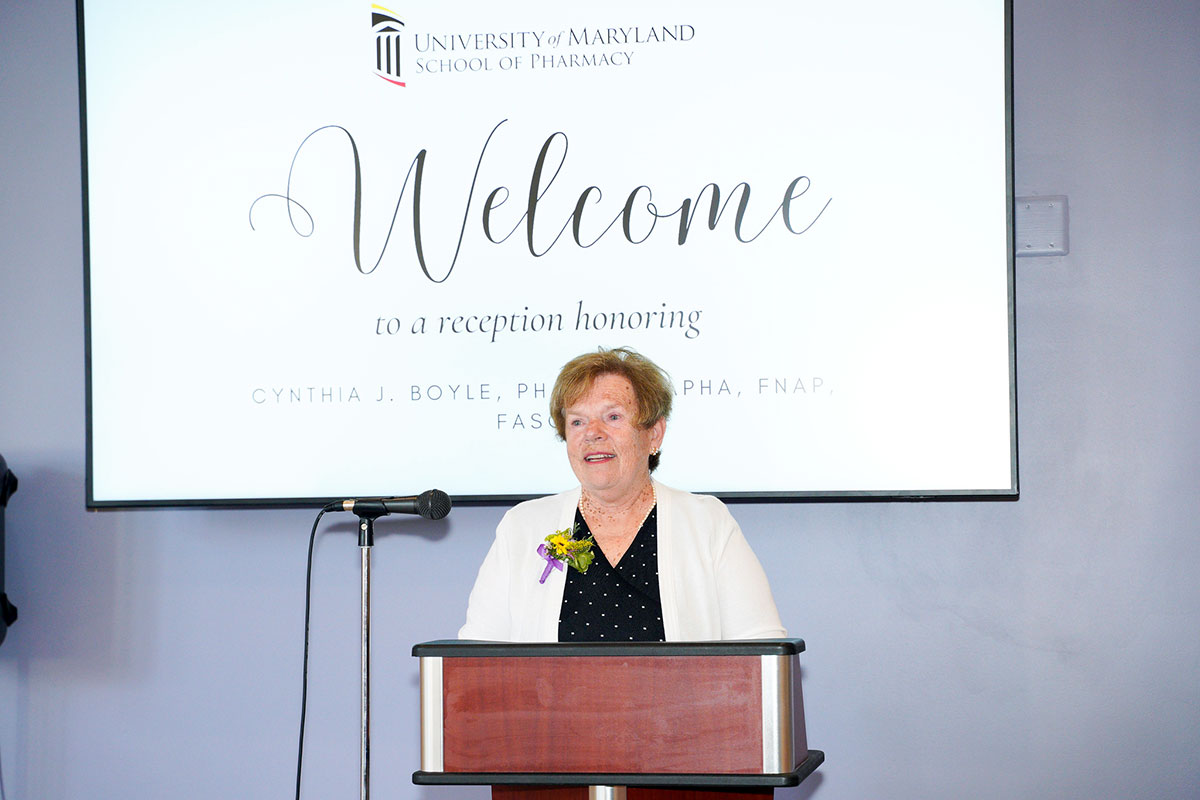 Cynthia Boyle stands at a podium speaking during a reception honoring her in Pharmacy Hall.