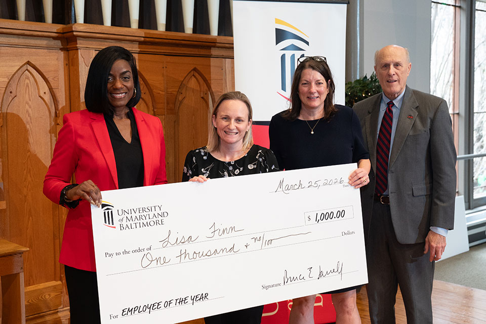 Lisa Finn, second from left, holds an oversized check while standing with UMB leadership at an Employee of the Year presentation.