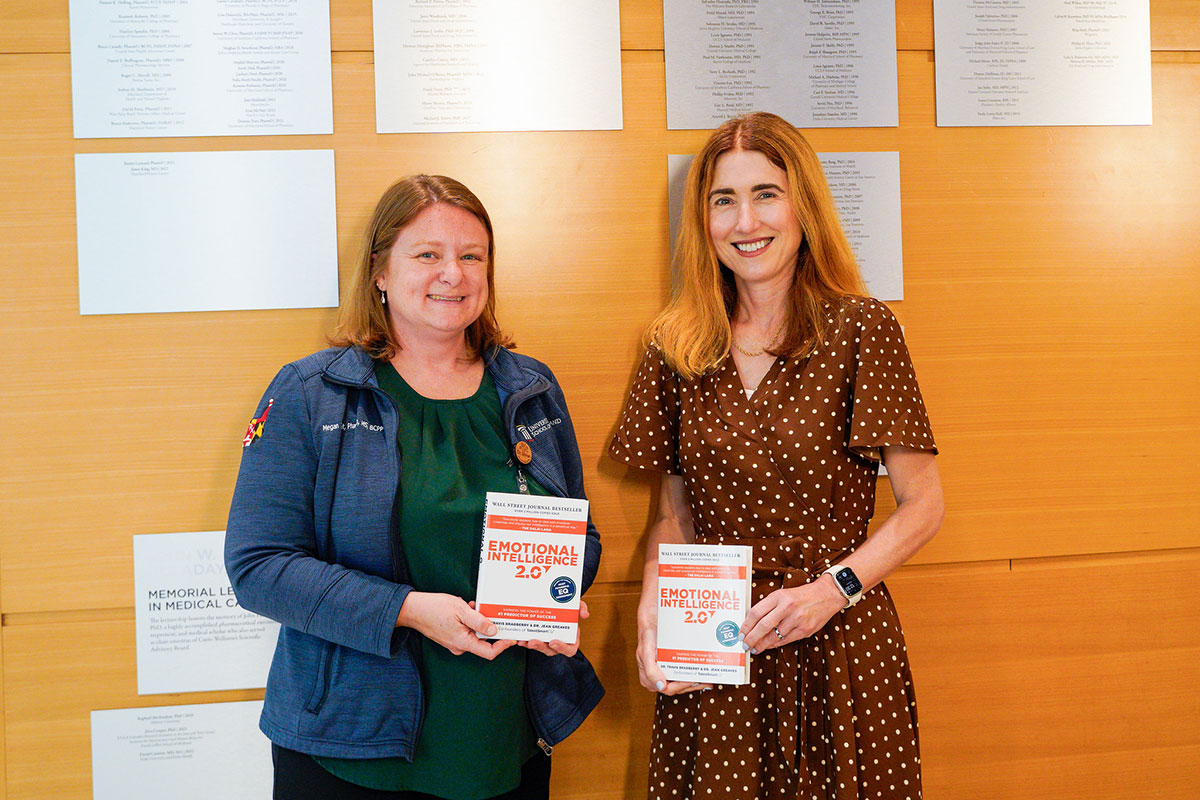 Megan Ehret and Dean Sarah Michel stand together holding copies of the book Emotional Intelligence 2.0.