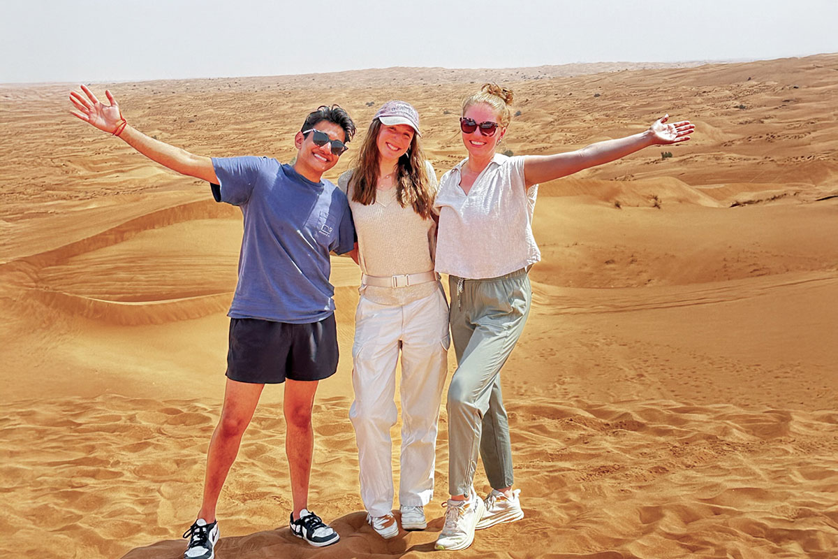 Vraj Patel with two colleagues standing in the desert under the sun during his rotation in Zambia.